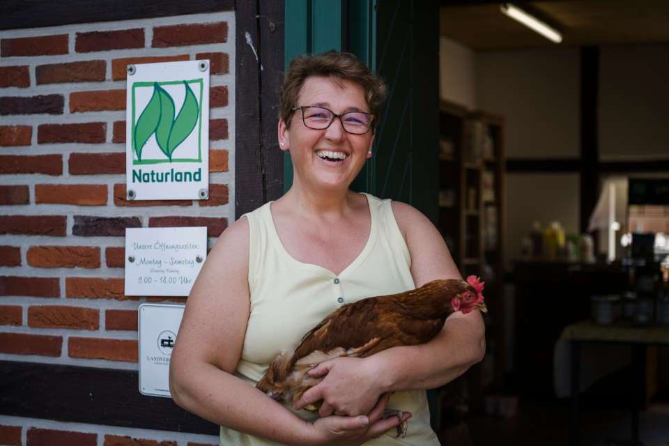 Frau trägt Huhn (Quelle: Stefan Simon, Beratung für Naturland)